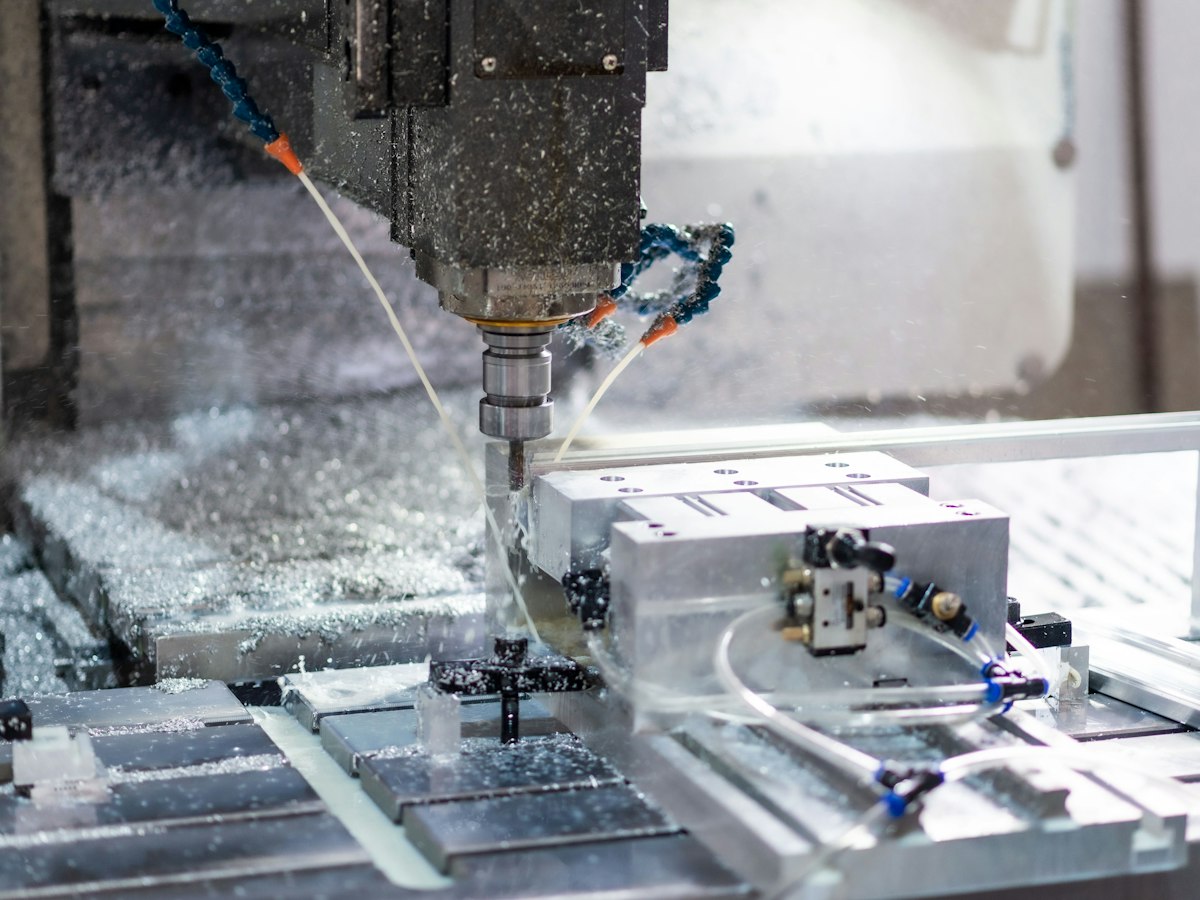 Five-axis CNC mill spraying coolant while cutting an aluminum block