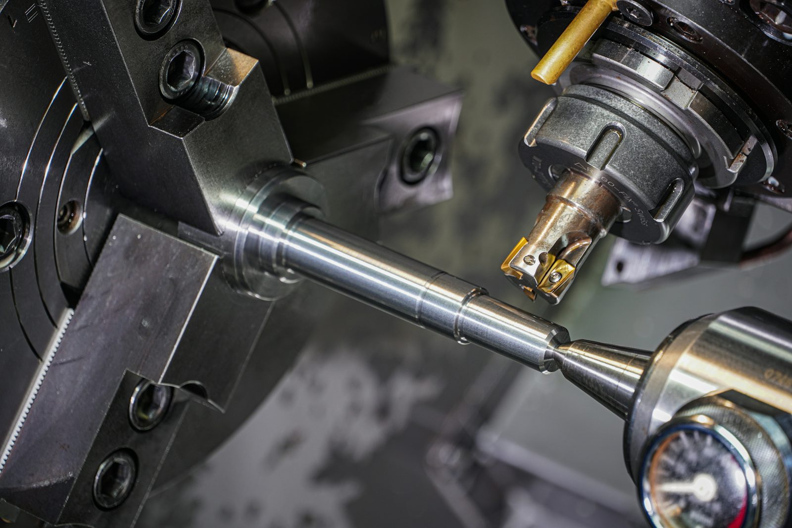 Close-up of a metal rod being turned in a lathe chuck by a cutting tool